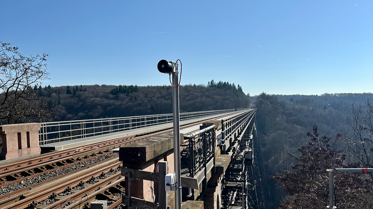 Technicians in safety gear inspecting train components with a tablet, while an advanced user interface displays real-time diagnostic data and system flow for predictive maintenance.